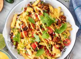 Chicken cheese loaded fries with melted cheddar sauce, crispy bacon, jalapeños, and fresh cilantro on golden crinkle-cut fries
